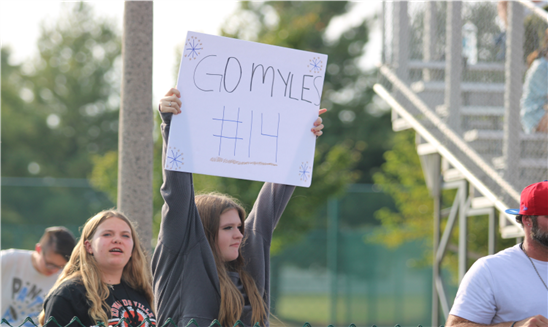 Aava Muensterman and Maisie Ingram cheer on Myles Wahl at an 8th grade football game.